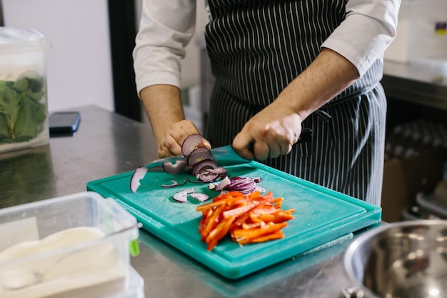 Fechar o chef masculino corta legumes no restaurante