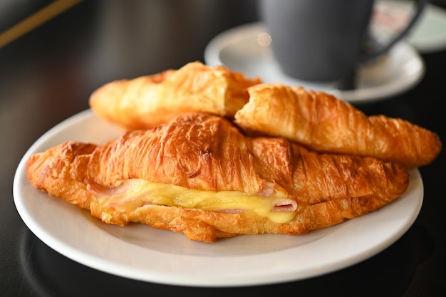 Fechar o queijo de presunto Croissant é um croissant de comida francesa com presunto e queijo na chapa branca e café