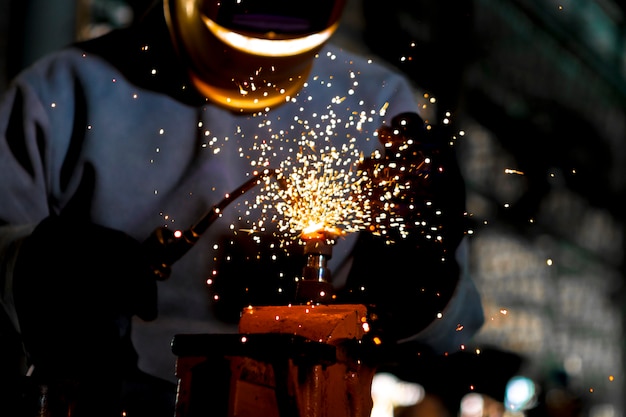 Fechar-se. Aço de gás de trabalho do soldador do soldador do trabalhador na indústria com as luvas da máscara da segurança e o equipamento de segurança.