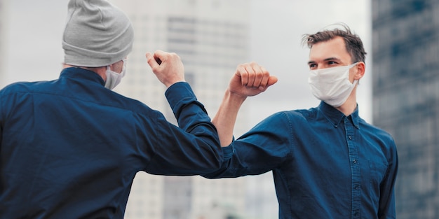 Fechar-se. amigos com máscaras protetoras cumprimentando-se. conceito de proteção à saúde