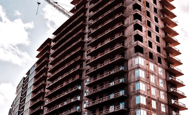 Fechar-se. Arranha-céu e guindaste de construção em um canteiro de obras.