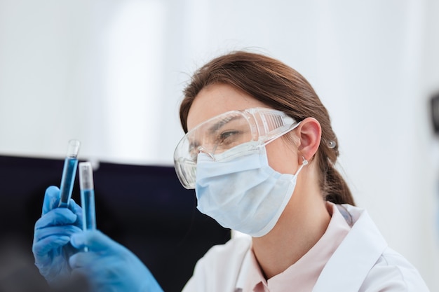 Fechar-se. cientista olhando para o líquido em tubos de ensaio. ciência e saúde.