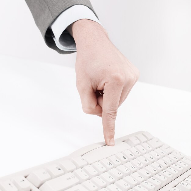 Foto fechar-se. empresário pressiona uma tecla no teclado do computador. isolado em fundo branco