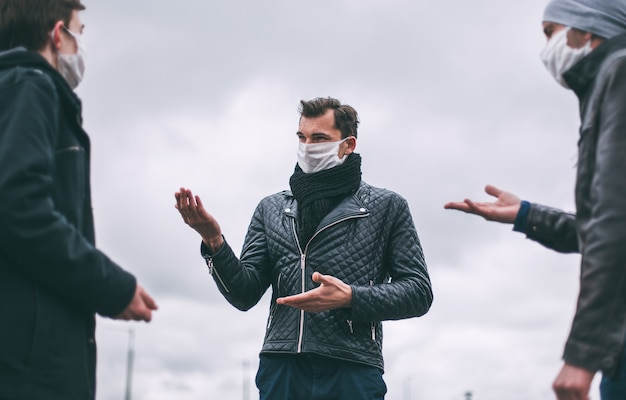 Fechar-se. jovens com máscaras protetoras falam em pé a uma distância segura