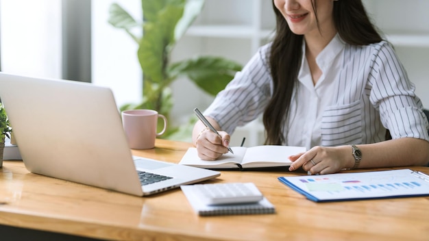 Fechar-se. Mão de empresária usando caneta tomando notas no escritório.