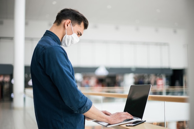 Fechar-se. um jovem com uma máscara protetora, usando um laptop. foto com uma cópia do espaço