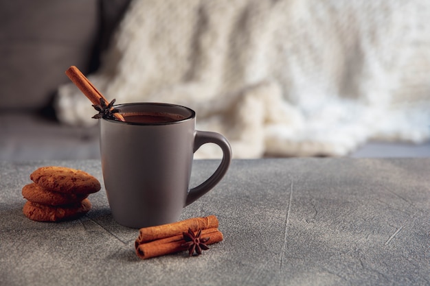 Fechar-se. xícara de chá ou café com canela e biscoitos isolados em fundo cinza e branco. o conceito de ambiente caseiro e conforto, férias, encontro romântico, inverno, natal ou ano novo.