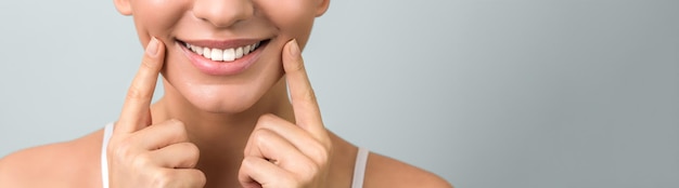 Fechar um belo sorriso saudável de uma jovem mulher em fundo azul claro com copyspace