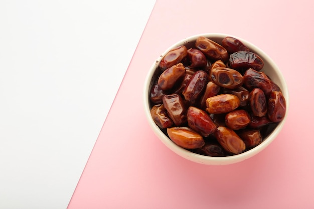 Foto fechas frescas en un plato sobre un fondo rosado