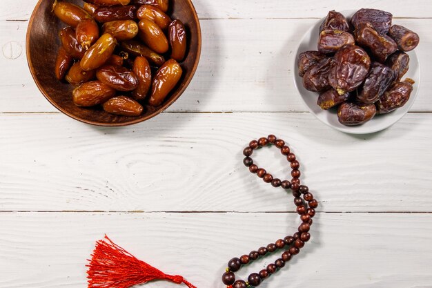 Fechas fruta y rosario en mesa de madera blanca Vista superior La fiesta musulmana del mes sagrado del Ramadán