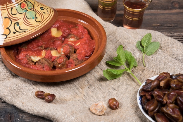 Foto fechas de frutas con carne y té en mesa.