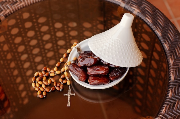 Fechas en una placa de vidrio con tapa y un rosario en una mesa de vidrio