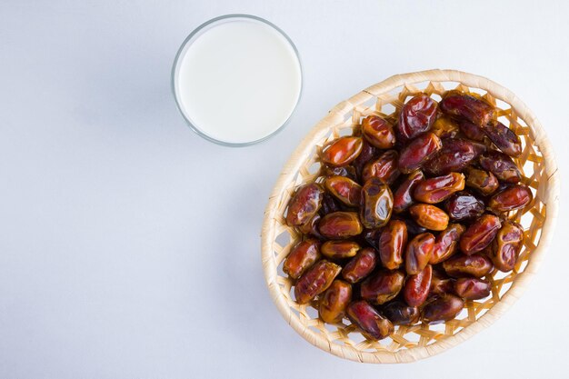 Fechas secas y leche sobre fondo blanco Fechas en canasta de madera y agua Concepto de comida de Ramadán