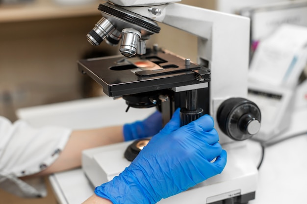 Feche a amostra de sangue de pesquisa de técnico de laboratório no microscópio.