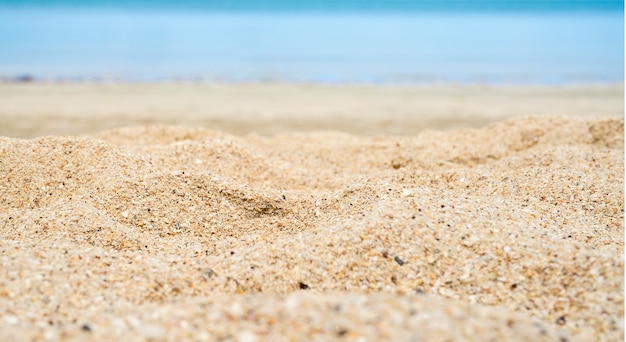 Feche a areia da praia com o mar ao fundo.