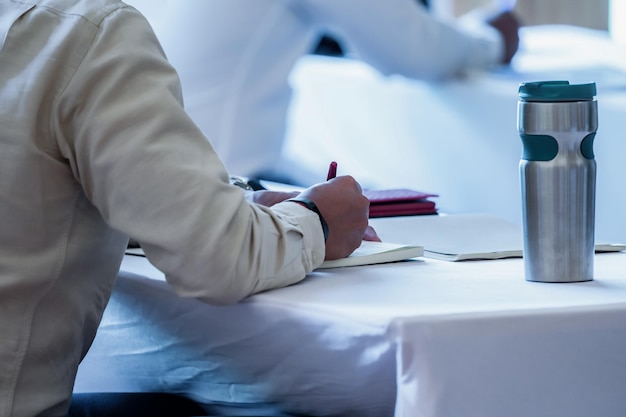 Foto feche a audiência do seminário com seu copo e gadget na mesa