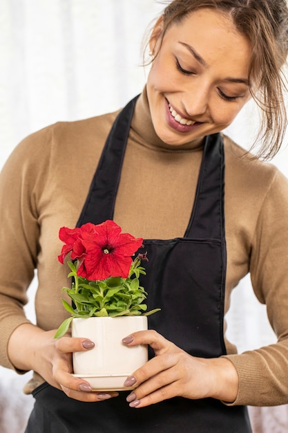 Feche a bela jardineira segura o vaso de cerâmica com petúnias florescendo nas mãos, foco em flores, florista jovem feliz cultivando flores, horta doméstica, hobby de jardinagem, floricultura