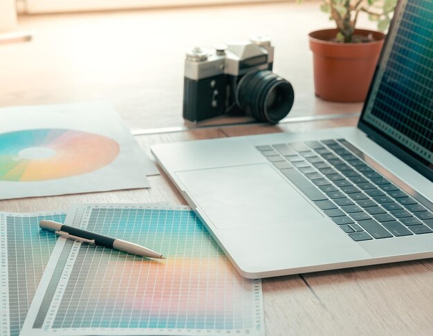 Foto feche a câmera do laptop e a paleta de cores na mesa do designer