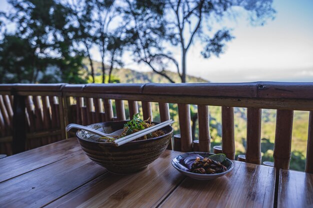 Foto feche a cobertura de macarrão khao soi com coxa de frango e aletria frita e bela vista da montanha khao soi ou khao soy é um prato chin haw servido no laos e no norte da tailândia