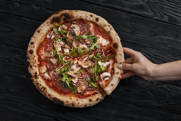 Feche a deliciosa pizza pequena recém-assada com cogumelos de queijo derretido e manjericão.