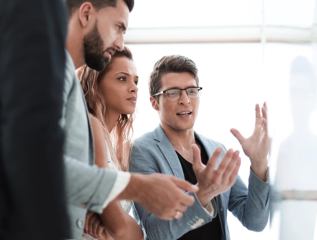 Feche a equipe de negócios falando em pé perto do flipchart