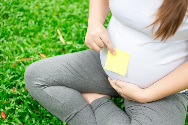 Feche a foto da nota na barriga de uma jovem grávida