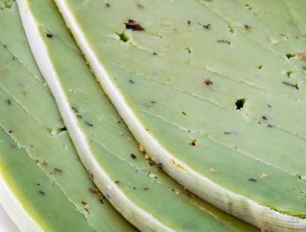 Feche a foto de fatias saborosas de queijo pesto verde