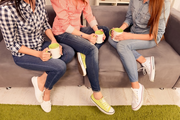 Feche a foto de três mulheres sentadas no sofá com xícaras