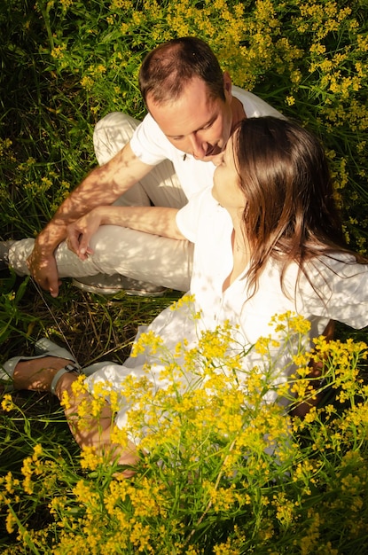 Feche a foto de um jovem casal relaxando na grama e flores amarelas