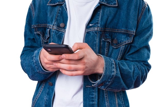 Feche a foto do homem com uma jaqueta jeans usando smartphone