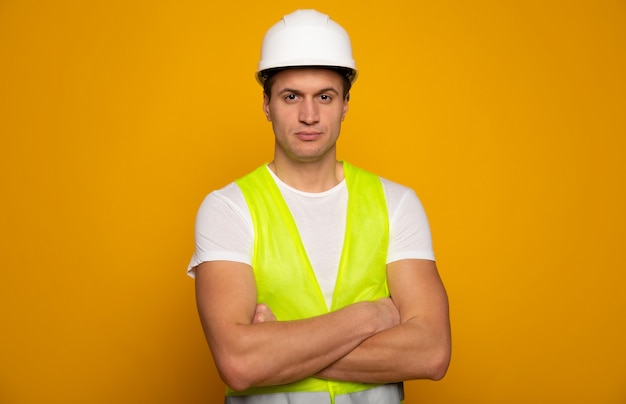 Feche a foto do jovem capataz ou arquiteto feliz e confiante no capacete de construção está posando isolado em fundo amarelo.