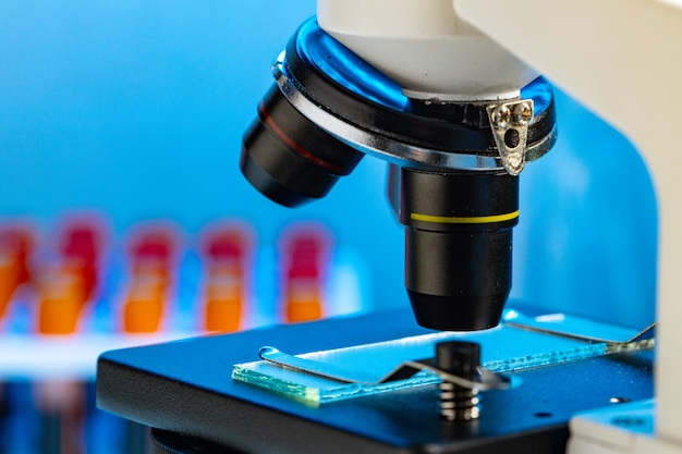 Foto feche a foto do microscópio com tubos de ensaio e amostras de sangue em laboratório