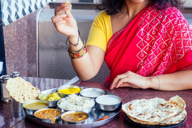 Feche a foto do thali vegetariano tradicional indiano de arroz dal batatas salada de tomate na placa de metal mãos femininas roti índia tortilla Chapati