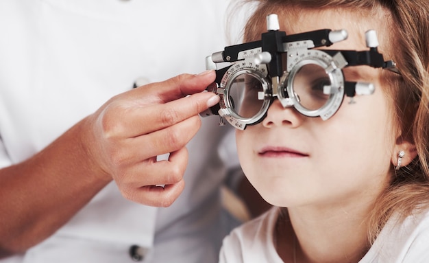 Feche a foto. Médico, verificando a visão da menina e ajustando o foróptero.