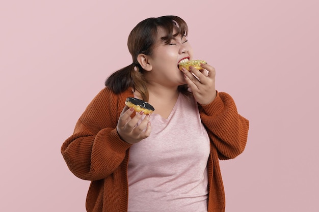 Foto feche a jovem asiática comendo e feliz desfrutando enquanto come lanche de rosquinha