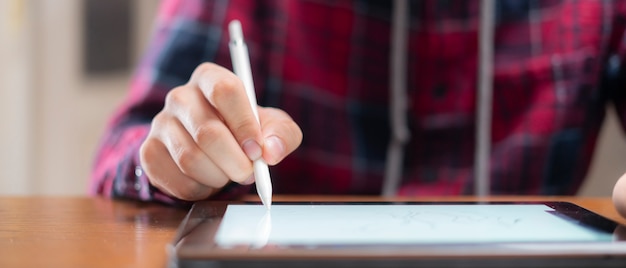Feche a mão com caneta digital desenhar no tablet
