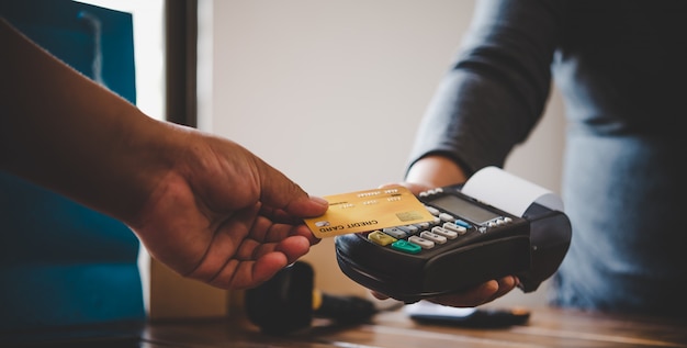 Foto feche a mão com cartão de crédito para pagar enviando o cartão de crédito para a equipe da máquina de furto de cartão de crédito. pagamento online