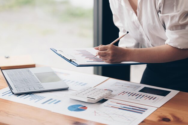 Feche a mão da mulher de negócios usando a calculadora para calcular os resultados financeiros e o orçamento da empresa conceito de auditoria de conta