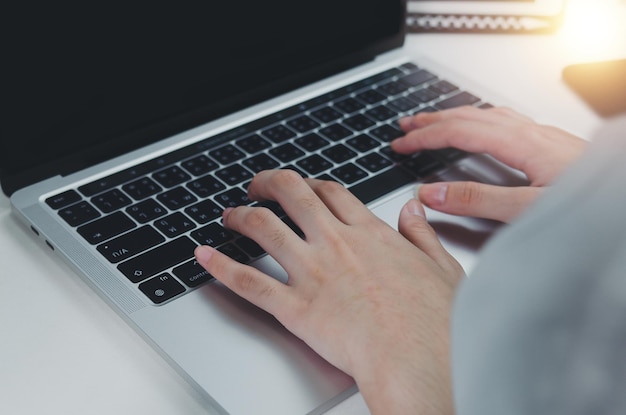 Feche a mão da mulher digitando o teclado do computador portátil na mesaTecnologia de negócios on-line e comunicação na mesa