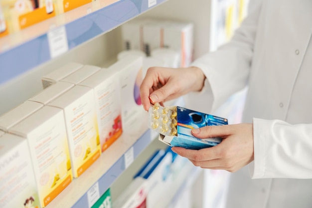 Feche a mão de um farmacêutico segurando óleo de tubarão em um blister