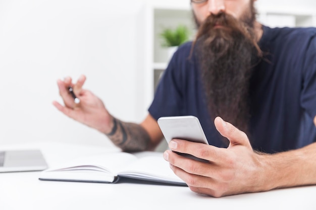 Feche a mão de um hipster barbudo segurando um smartphone