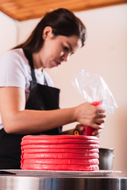 Feche a mão de uma mulher, decorando o bolo na cozinha.