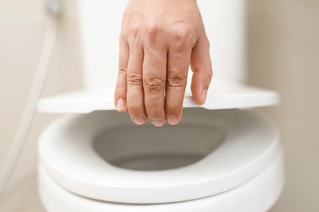 Feche a mão de uma mulher fechando a tampa de um assento de vaso sanitário Conceito de higiene e cuidados de saúde