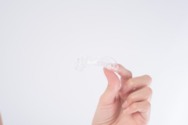 Feche a mão de uma mulher segurando o aparelho invisalign em branco