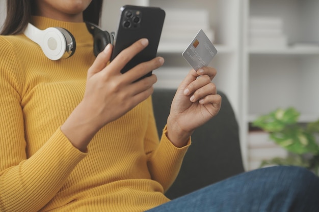 Feche a mão de uma mulher usando cartão de crédito e laptop smartphone para fazer compras online