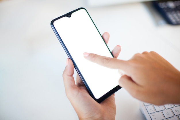 Foto feche a mão de uma mulher usando um telefone inteligente com tela em branco