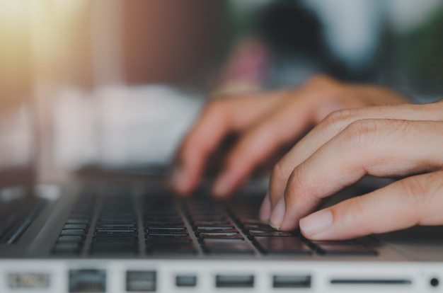 Foto feche a mão do empresário digitando um teclado de laptop de computador. trabalho usando um computador, pesquisando na web, online, comunicando-se com negócios de tecnologia de conceito.