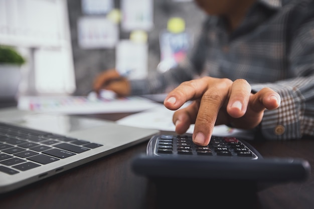 Feche a mão do homem de negócios, pressione a calculadora