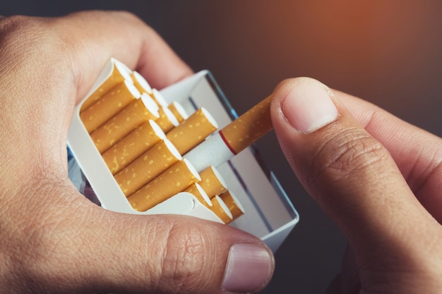 Feche a mão do homem segurando descole-o do maço de cigarros, prepare-se para fumar um cigarro. linha de embalagem.