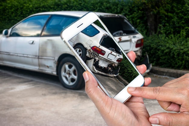 Feche a mão do homem segurando o smartphone e tirar foto de acidente de carro